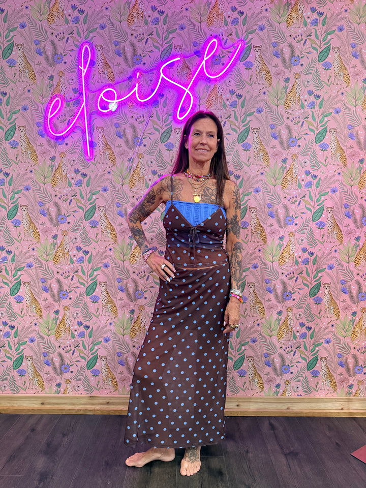 Woman wearing matching brown and blue polka dot set on pink floral background