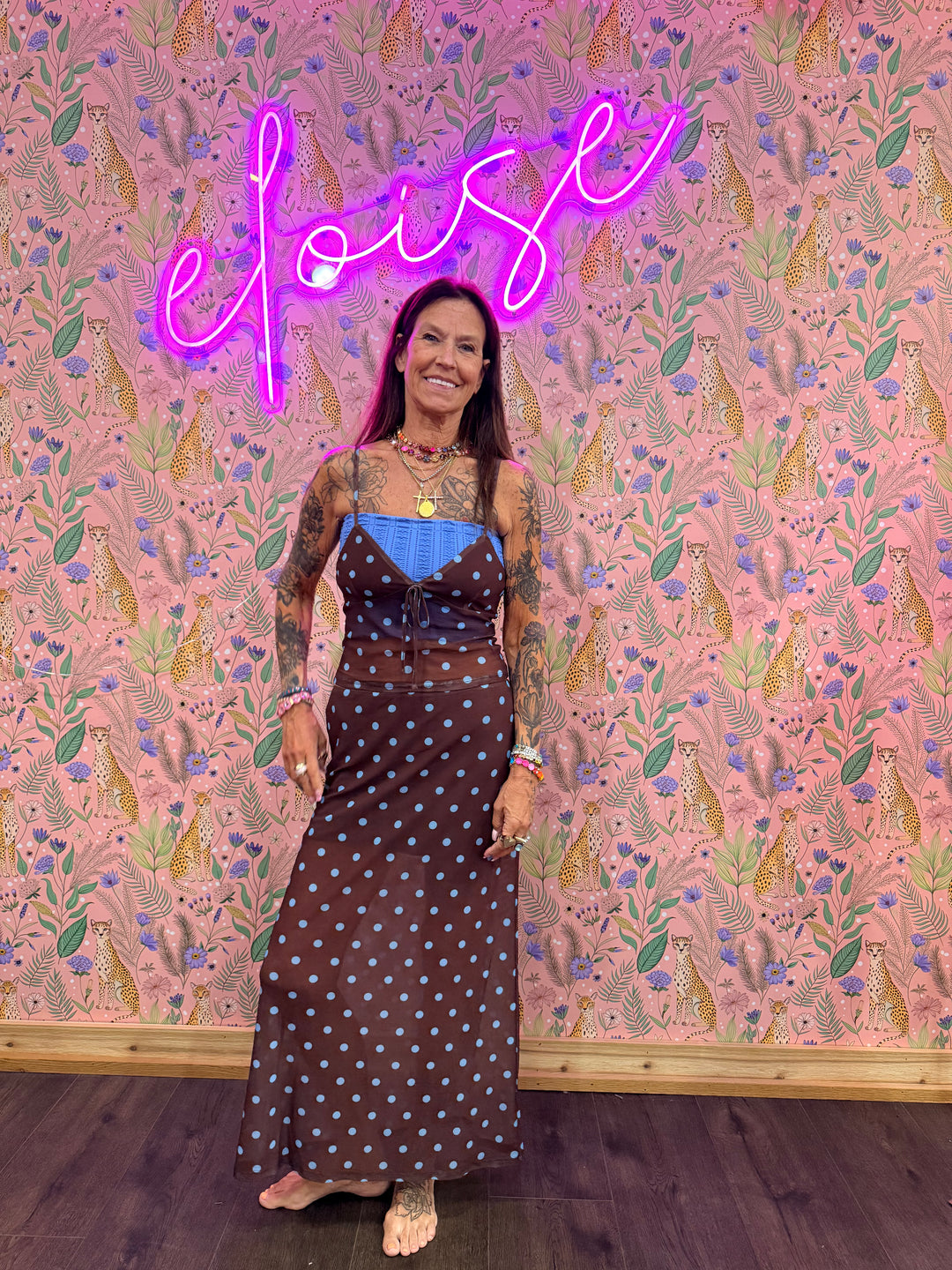 Woman wearing brown and blue polka dot matching set on pink floral background