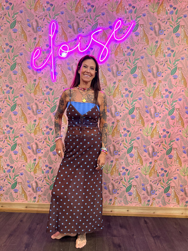 Woman wearing brown and blue polka dot matching set on pink floral background