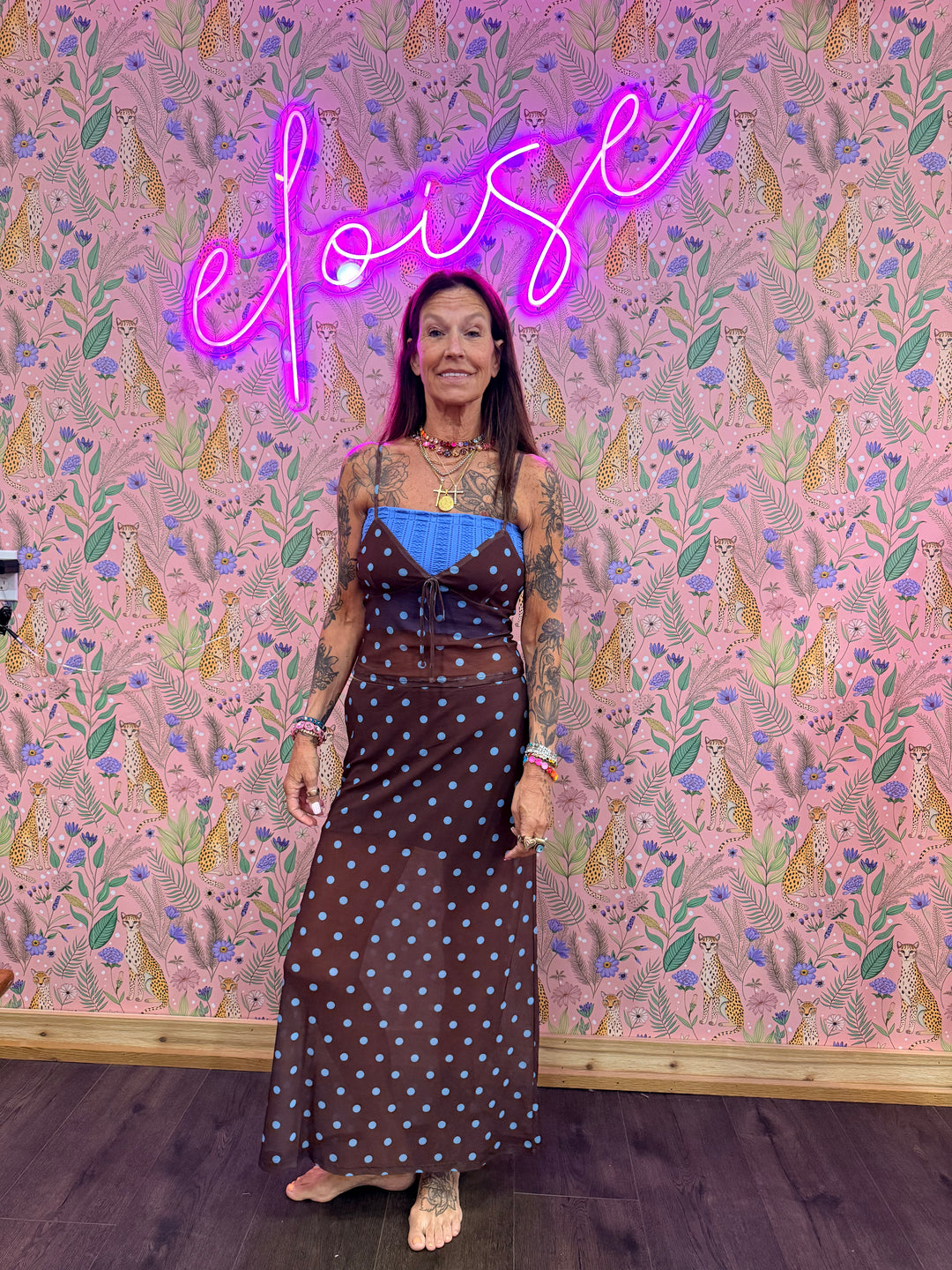 Woman wearing brown and blue polka dot matching set on pink floral background
