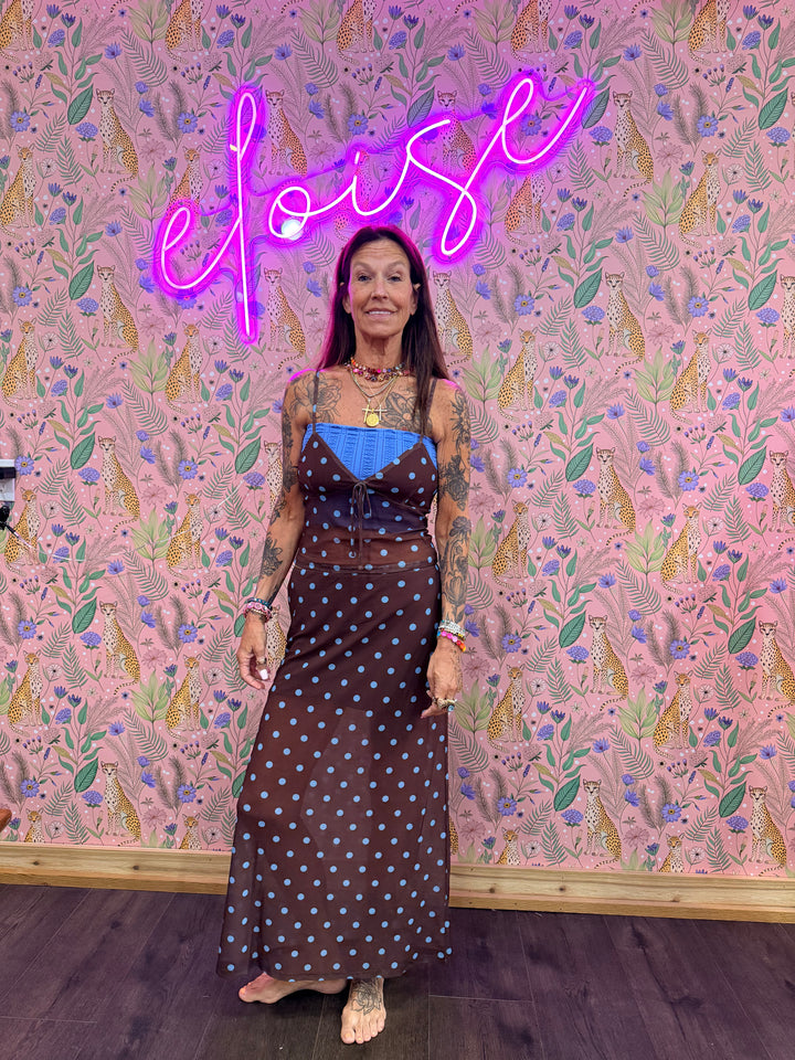 Woman wearing brown and blue polka dot matching set on pink floral background
