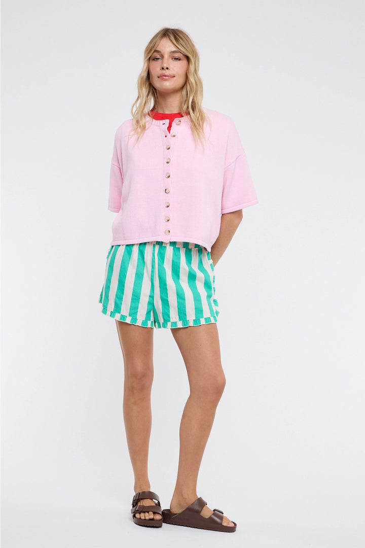 Woman wearing a pink shirt and green striped shorts on a white background