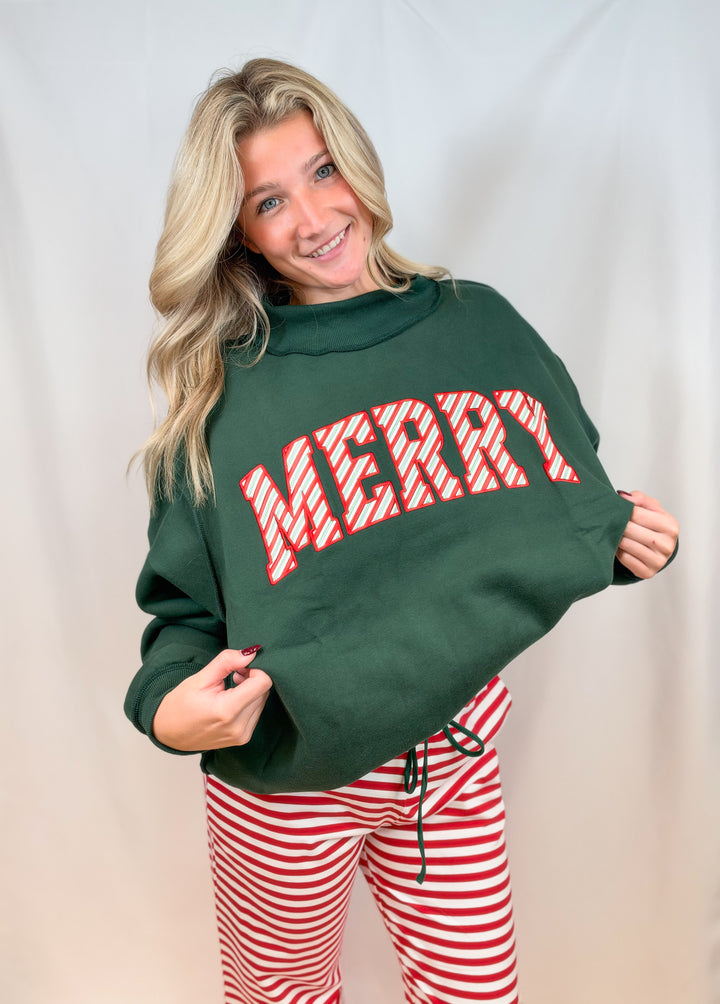 Woman wearing green mock neck sweatshirt with red and white striped &