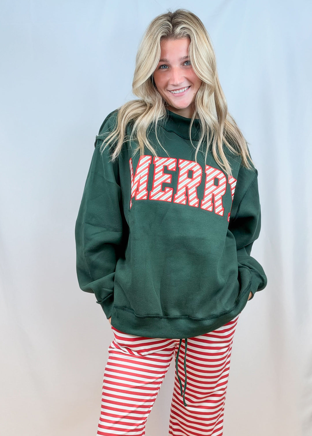 Woman wearing green mock neck sweatshirt with red and white stripe &