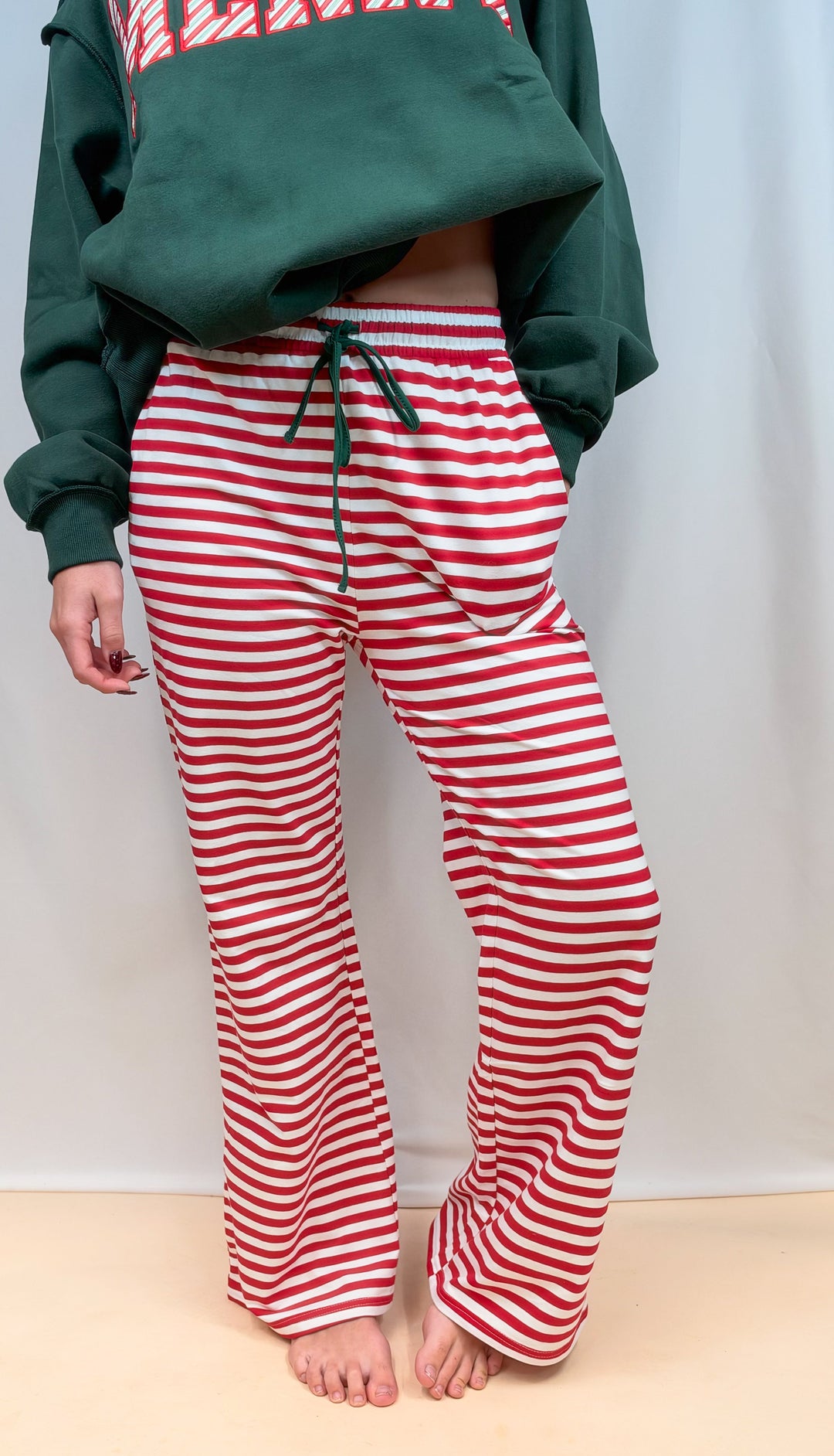 Woman shown from waist down wearing red and white stripe pants on plain background