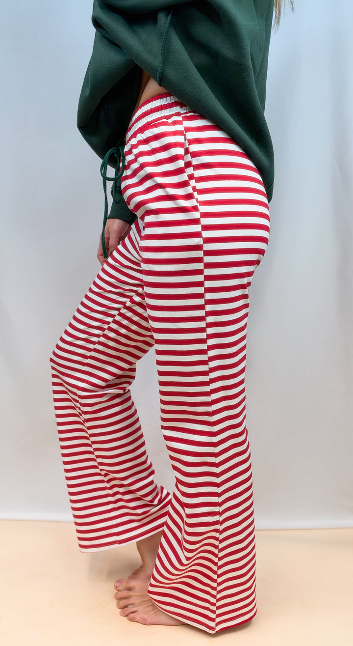 Woman shown from side view wearing red and white stripe pants on plain background