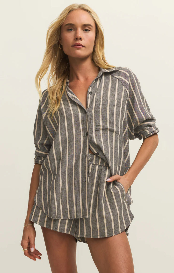 Woman wearing a striped shirt and shorts on a plain background