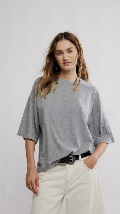 Woman wearing grey oversized tee and beige pants on white background