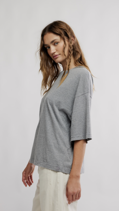 Woman wearing grey oversized tee and beige pants on white background