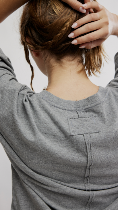 Close up of back of woman wearing grey oversize tee on white background