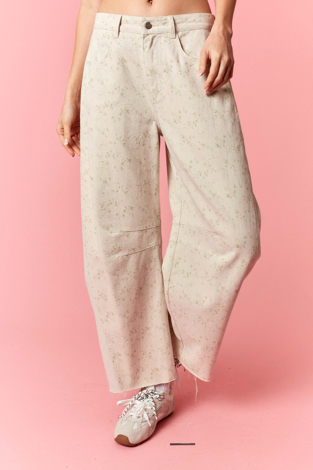 Person wearing light-colored wide-leg pants on a pink background