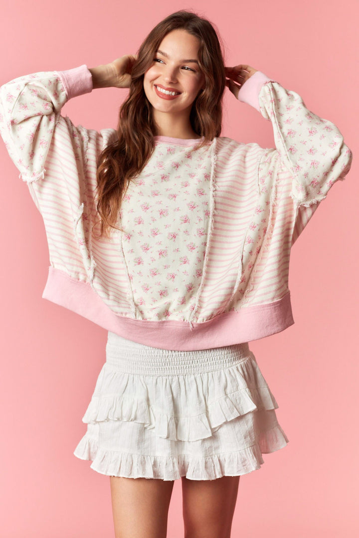 woman wearing pink floral and pinstripe top on pink background