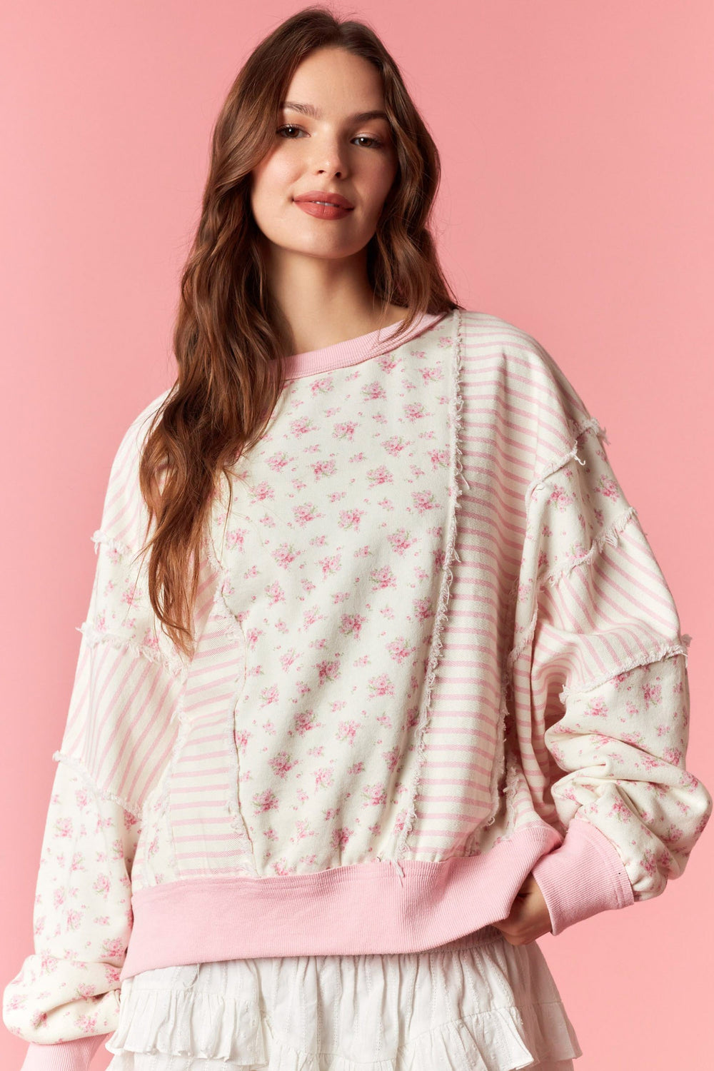 Woman wearing a pink and white patterned outfit on a pink background