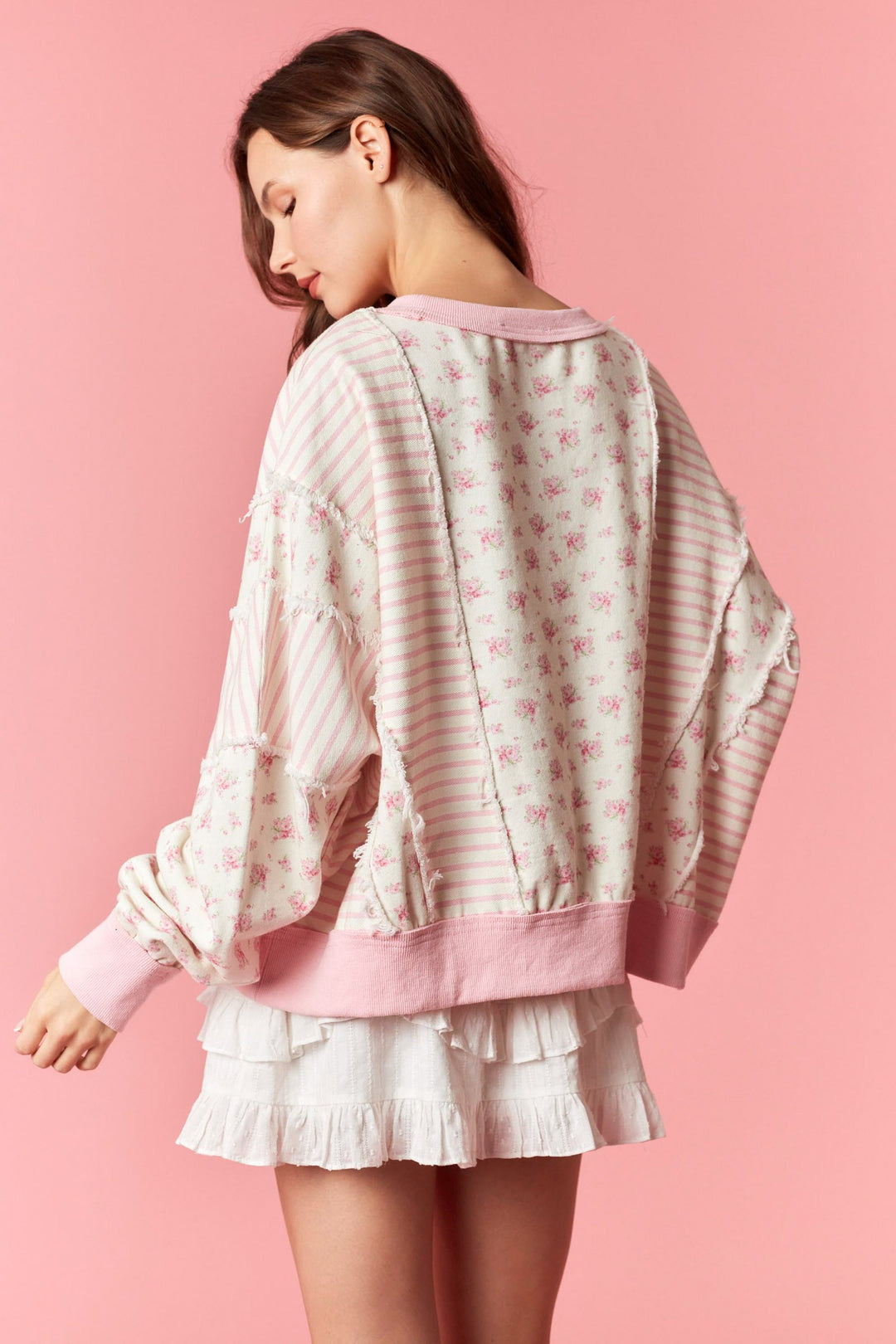 Woman wearing a light pink and white patterned outfit on a pink background