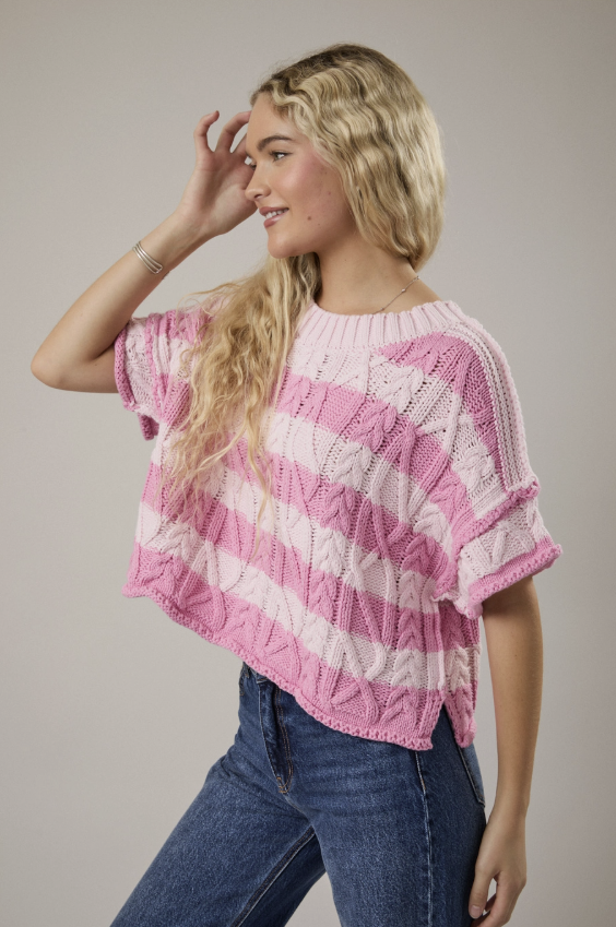 woman wearing pink stripe sweater top on plain background