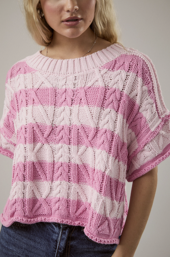 Person wearing a pink and white knitted sweater against a neutral background
