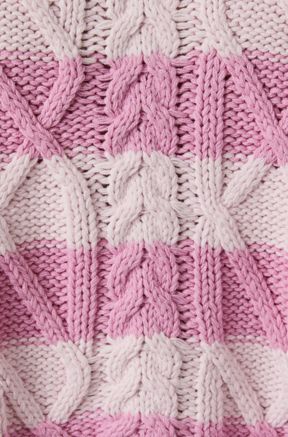 Close-up of pink and white knitted fabric with cable pattern