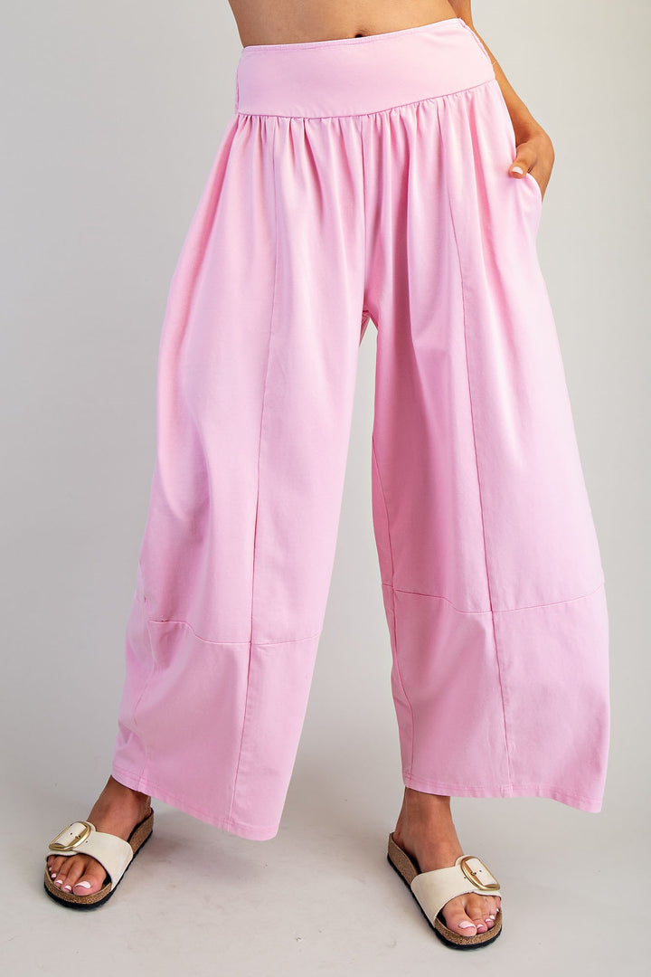 Woman wearing pink pans and white sandals on plain background