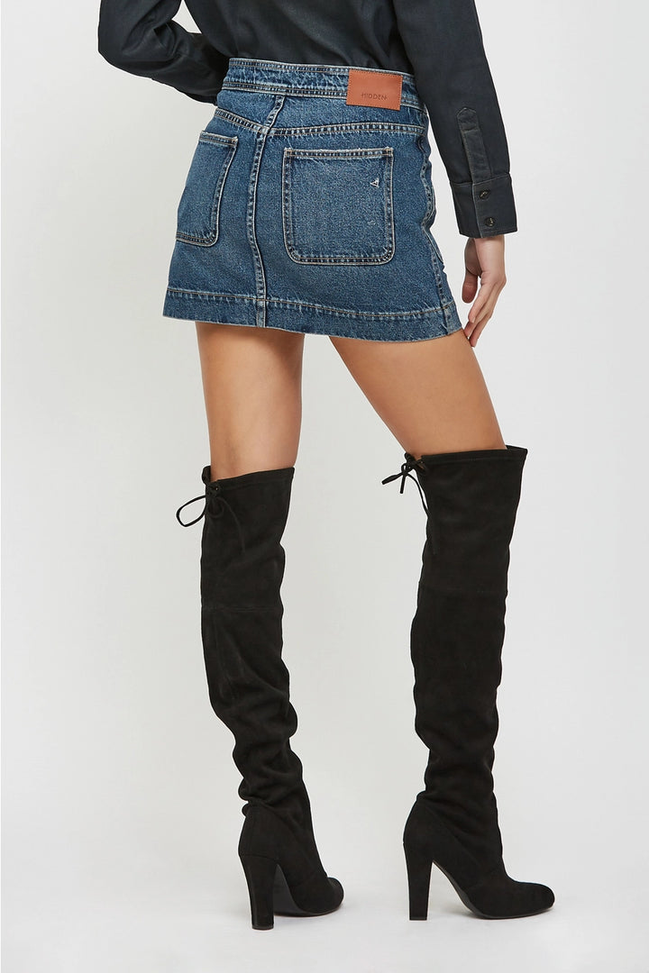 Person wearing a denim skirt and black knee-high boots on a white background