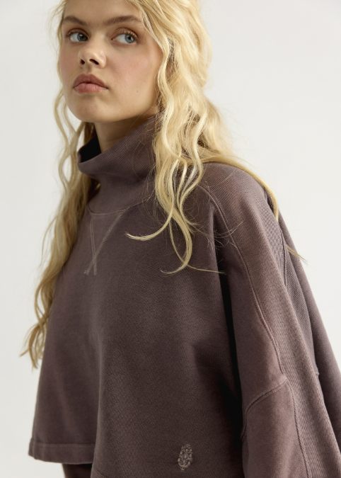 Close up of woman wearing brown mock neck sweatshirt on white background