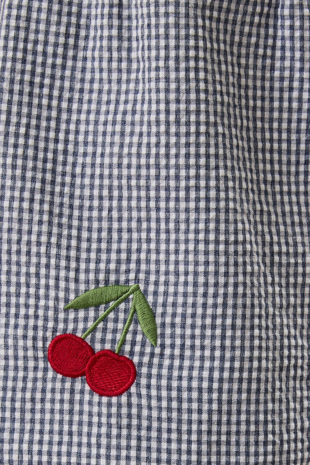 Embroidered cherries on a blue and white checkered fabric
