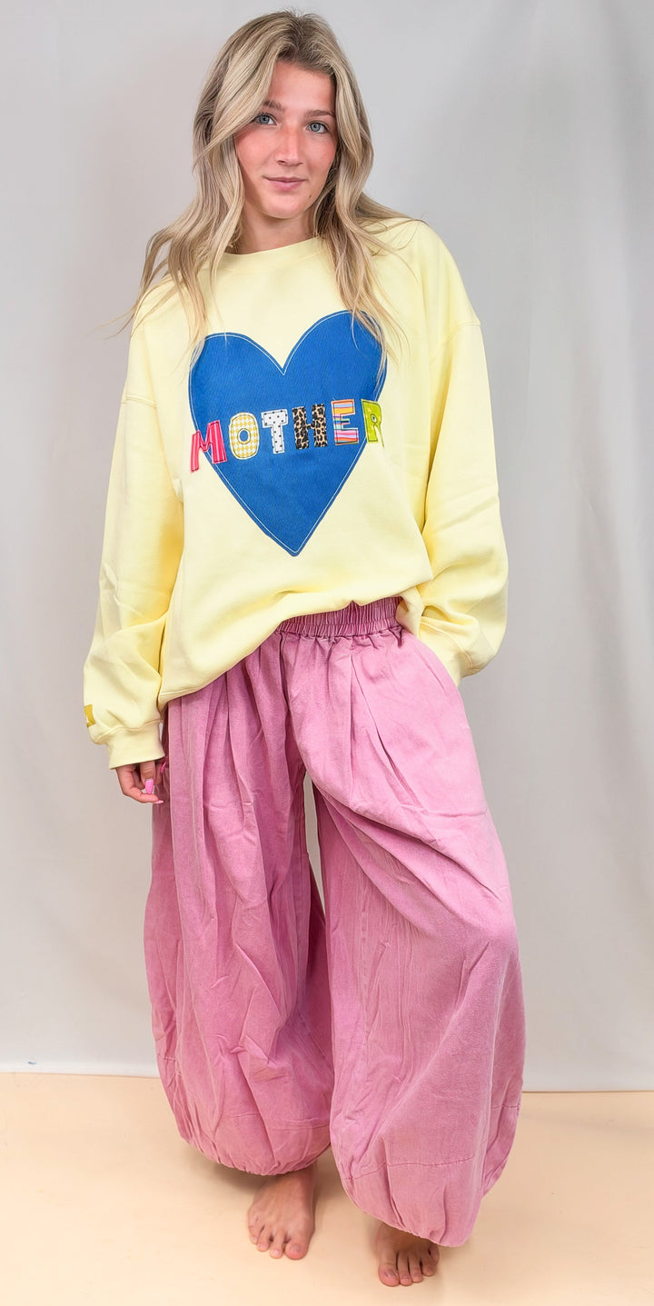 Woman wearing pale yellow sweatshirt with &
