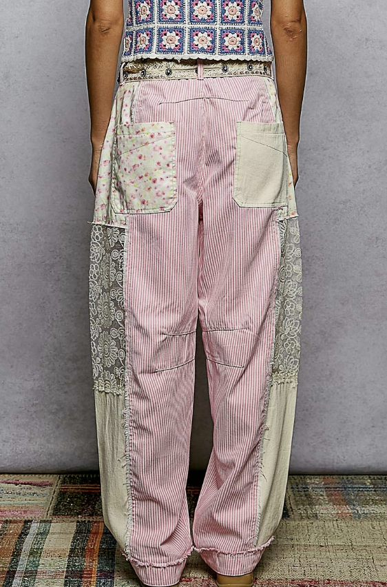 Person wearing patchwork pants with a patterned top against a plain background