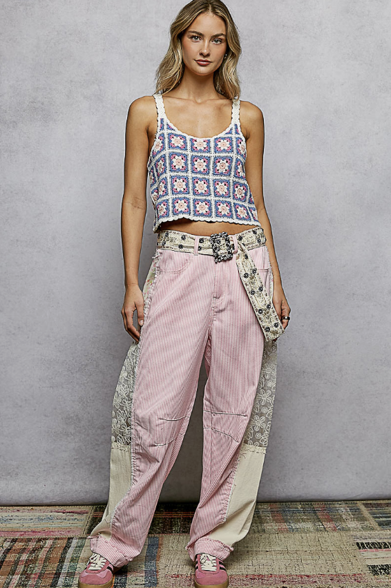 Woman wearing a patterned top and pink pants against a gray background