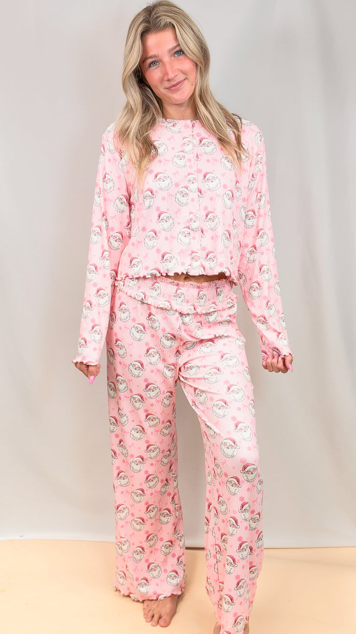 Woman wearing pink christmas pajamas with vintage santa and bows on plain background