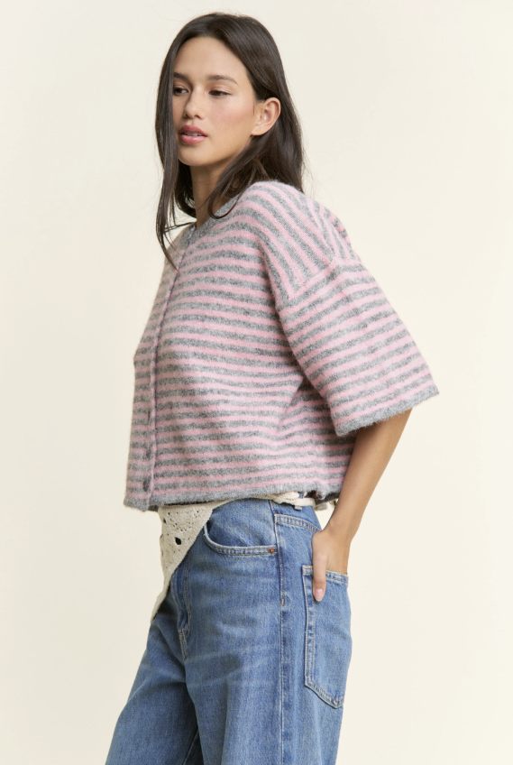 Woman wearing a striped sweater and jeans on a plain background