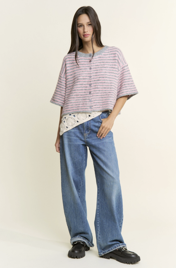 Woman wearing a striped shirt and blue jeans on a plain background