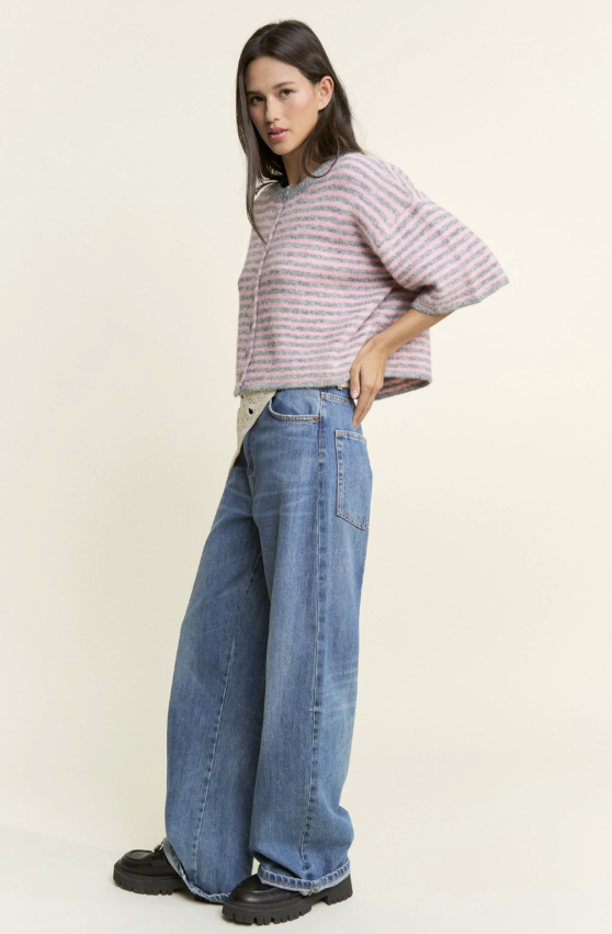 Woman wearing a striped shirt and wide-leg jeans on a plain background