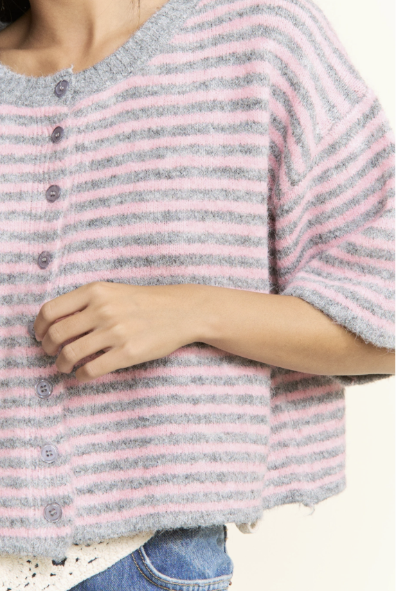 Close-up of a person wearing a pink and gray striped sweater with a blurred background