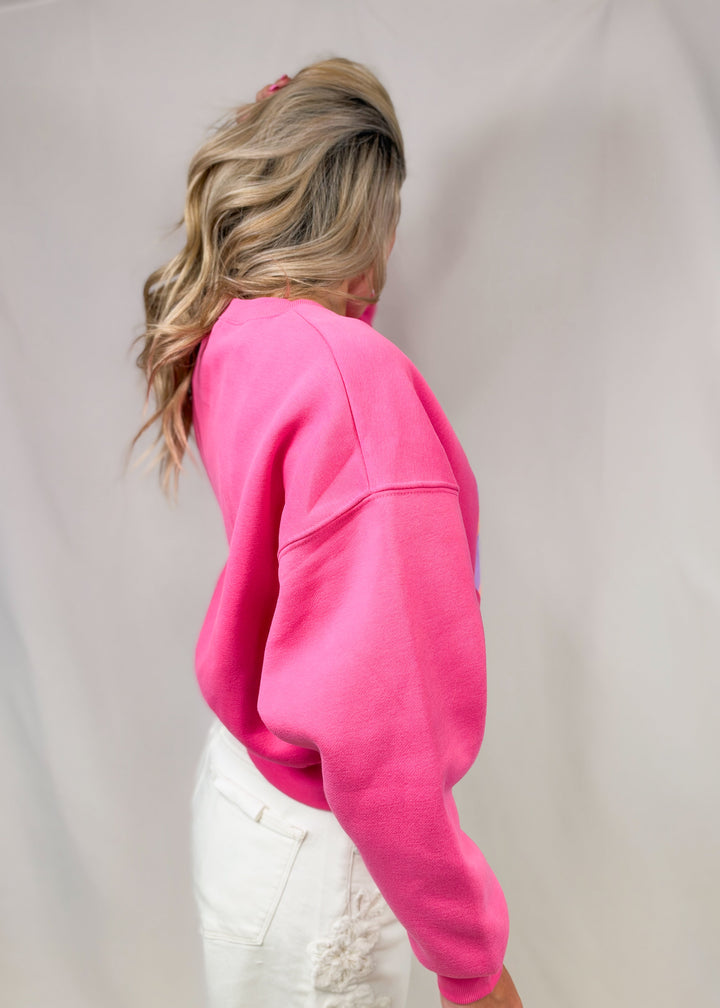 Woman wearing pink sweatshirt with white pants on plain background