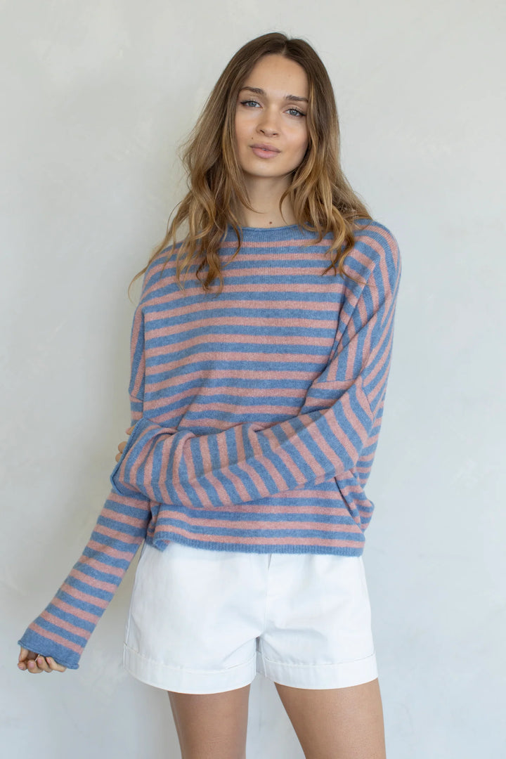 Woman wearing stripe sweater and white shorts on plain background