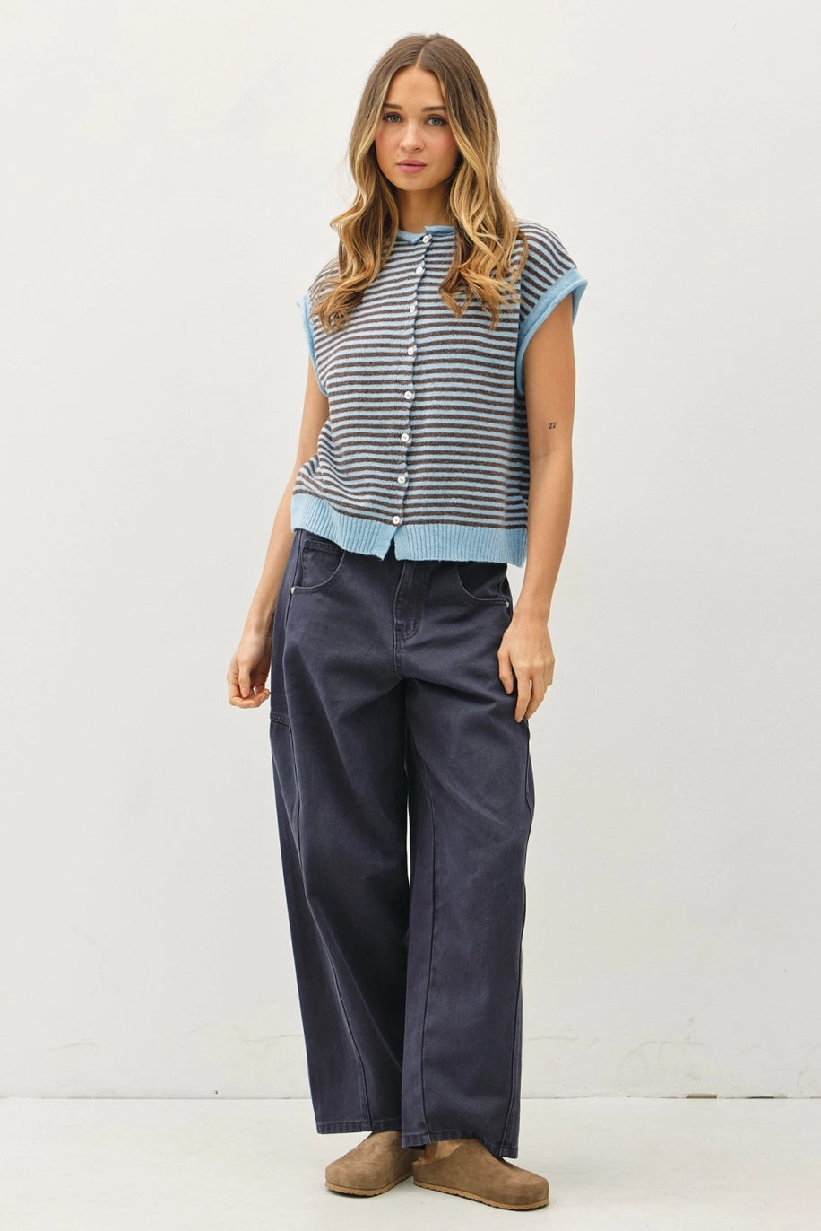 Woman wearing a striped shirt and dark pants against a white background