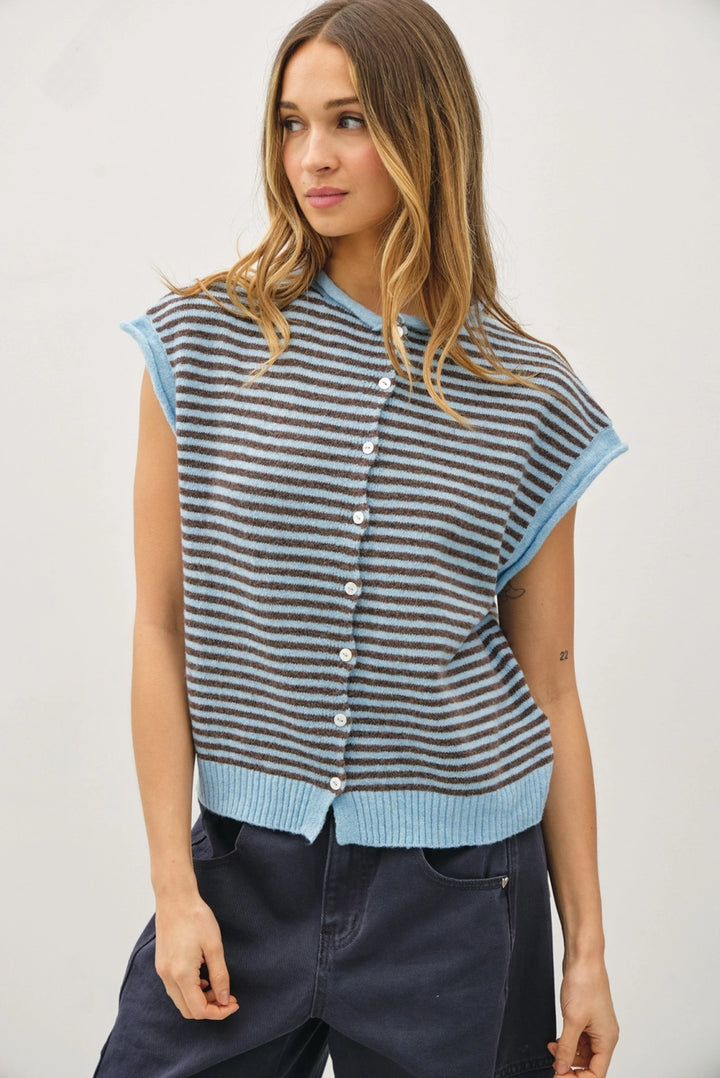 Woman wearing a striped sleeveless cardigan with buttons on a plain background