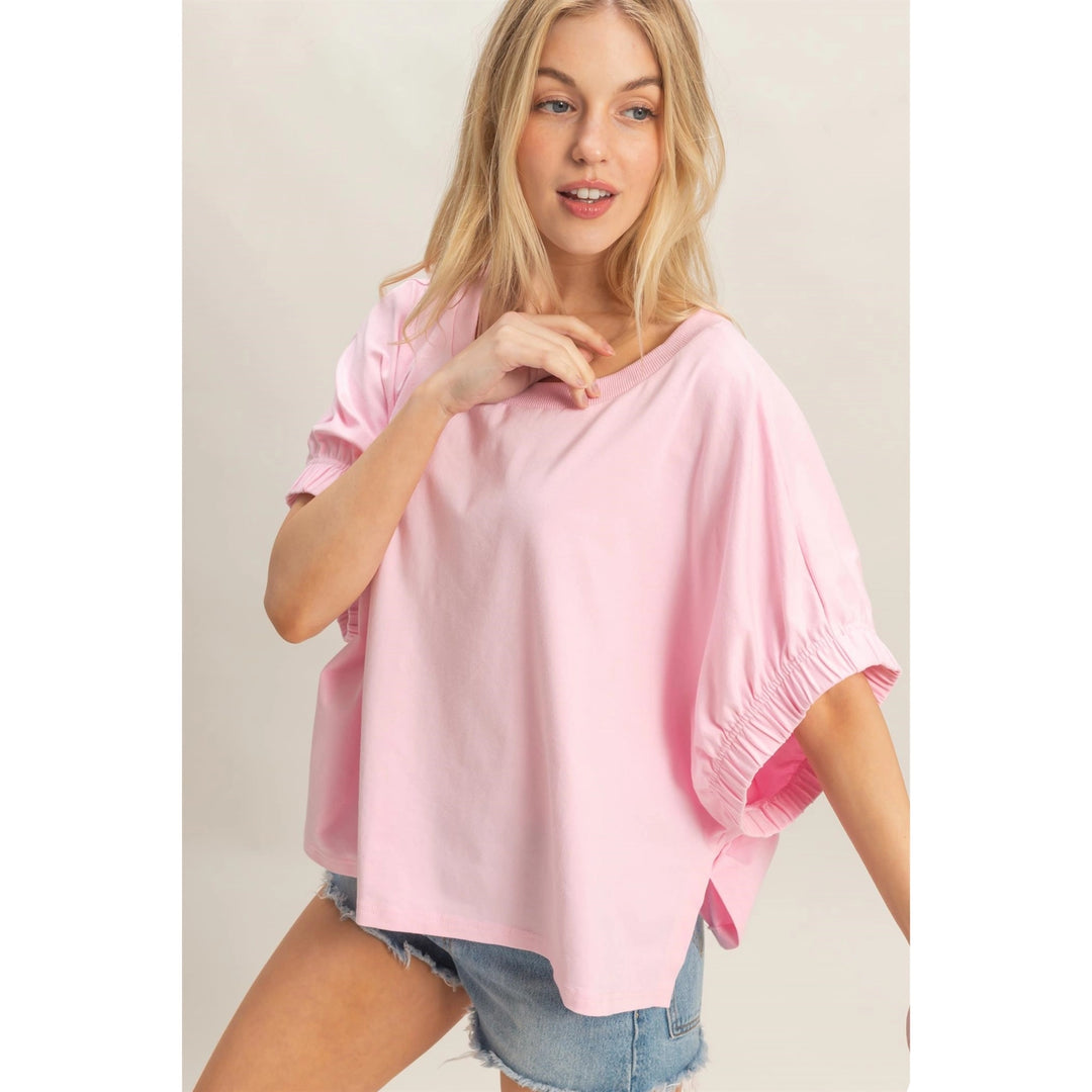 Woman wearing a pink top and denim shorts on a plain background