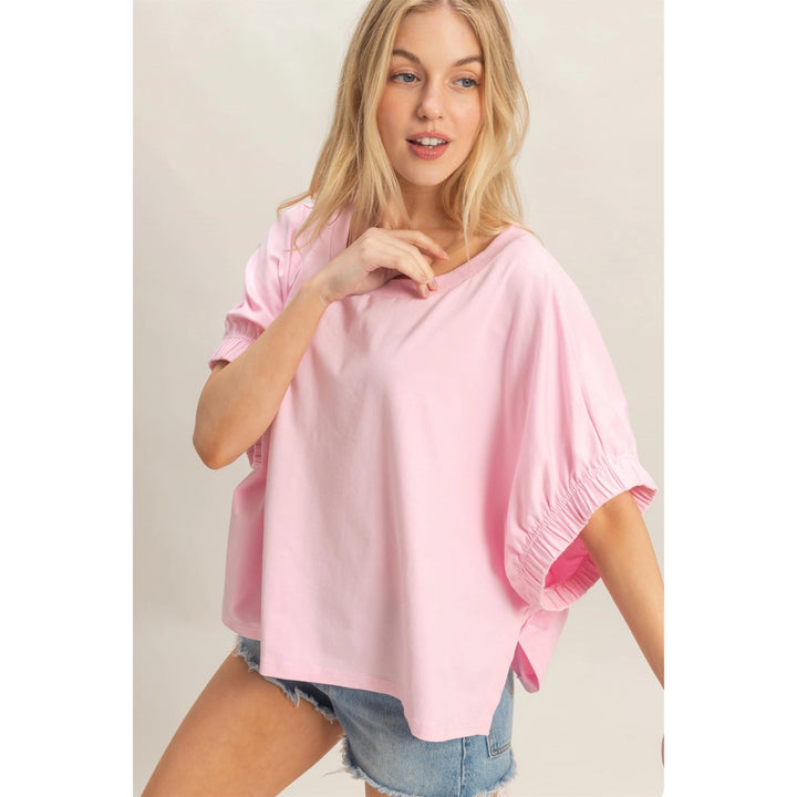 Woman wearing a pink top and denim shorts on a plain background