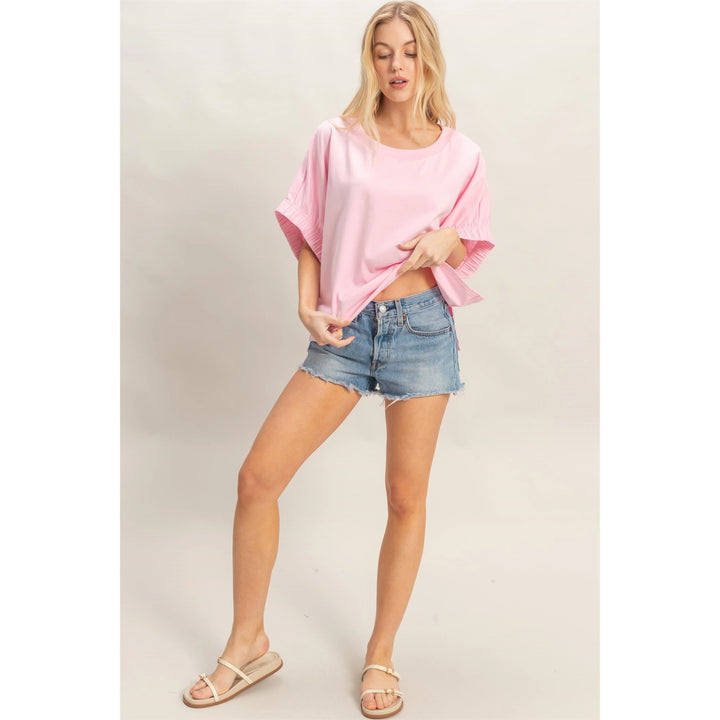 Woman wearing a pink top and denim shorts on a plain background