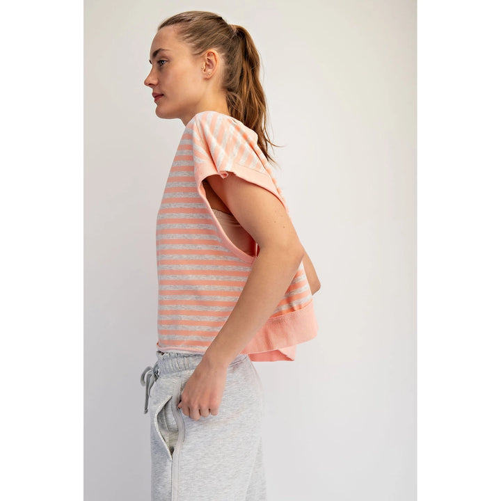 Woman wearing a pink and white striped shirt with gray pants on a light gray background