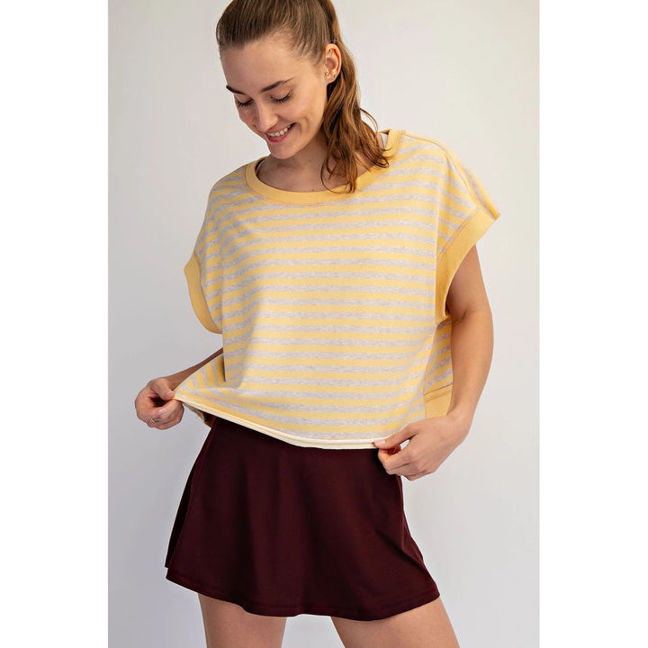 Woman wearing a yellow striped shirt and maroon skirt on a plain background