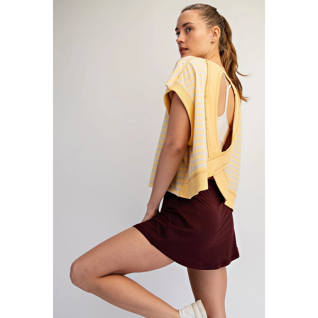 Woman wearing a yellow striped top and maroon shorts on a plain background