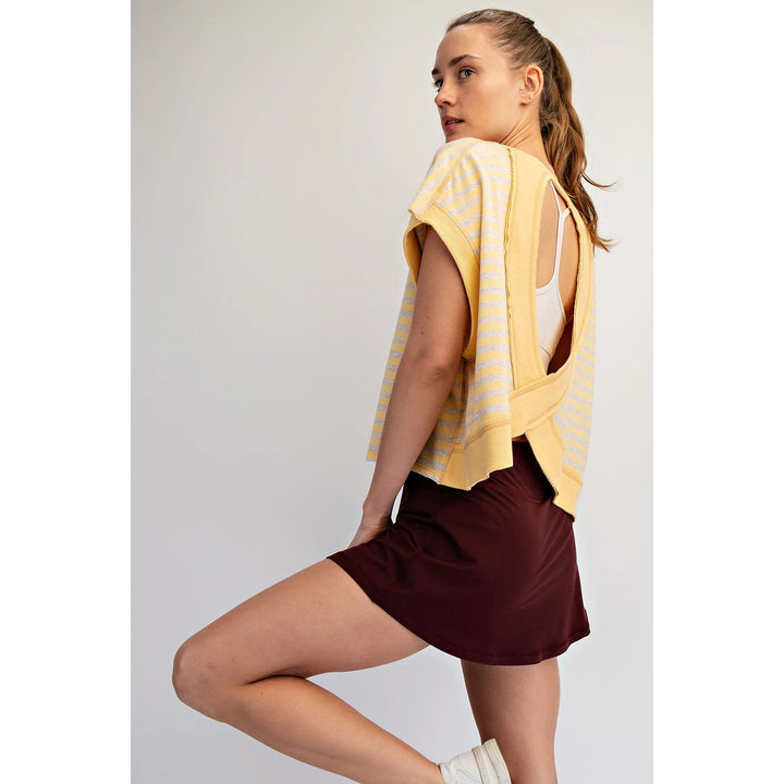 Woman wearing a yellow striped top and maroon shorts on a plain background