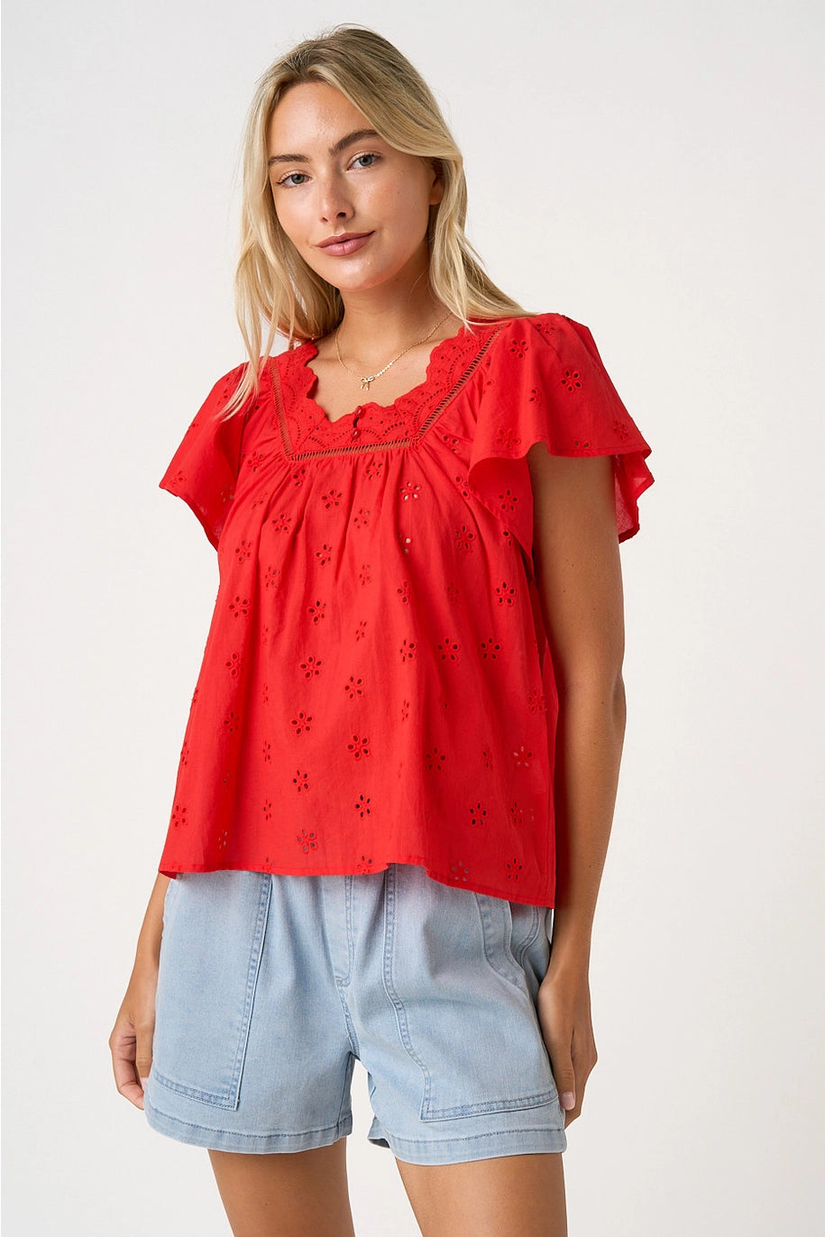Woman wearing a red top and light blue shorts on a white background