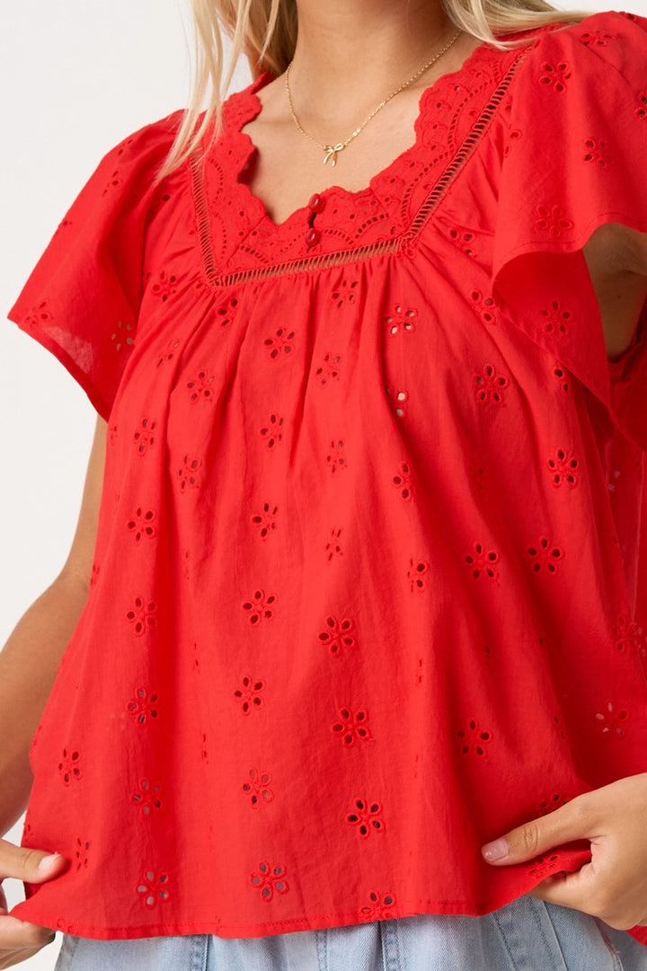 Red blouse with floral cut-out details worn by a person.