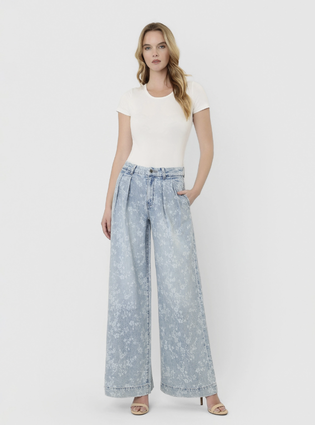 Woman wearing light blue floral pants and a white top on a white background