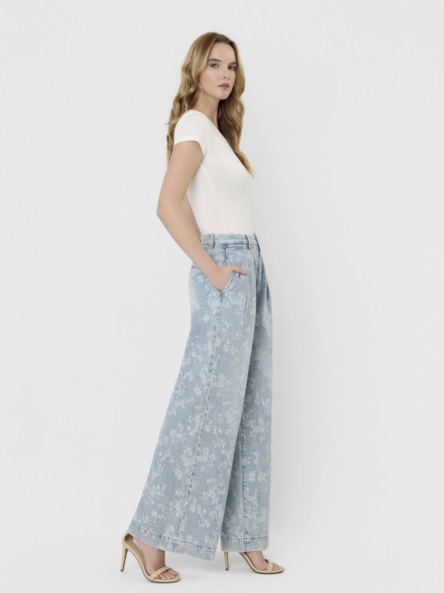 Woman wearing a white top and light blue wide-leg jeans on a white background