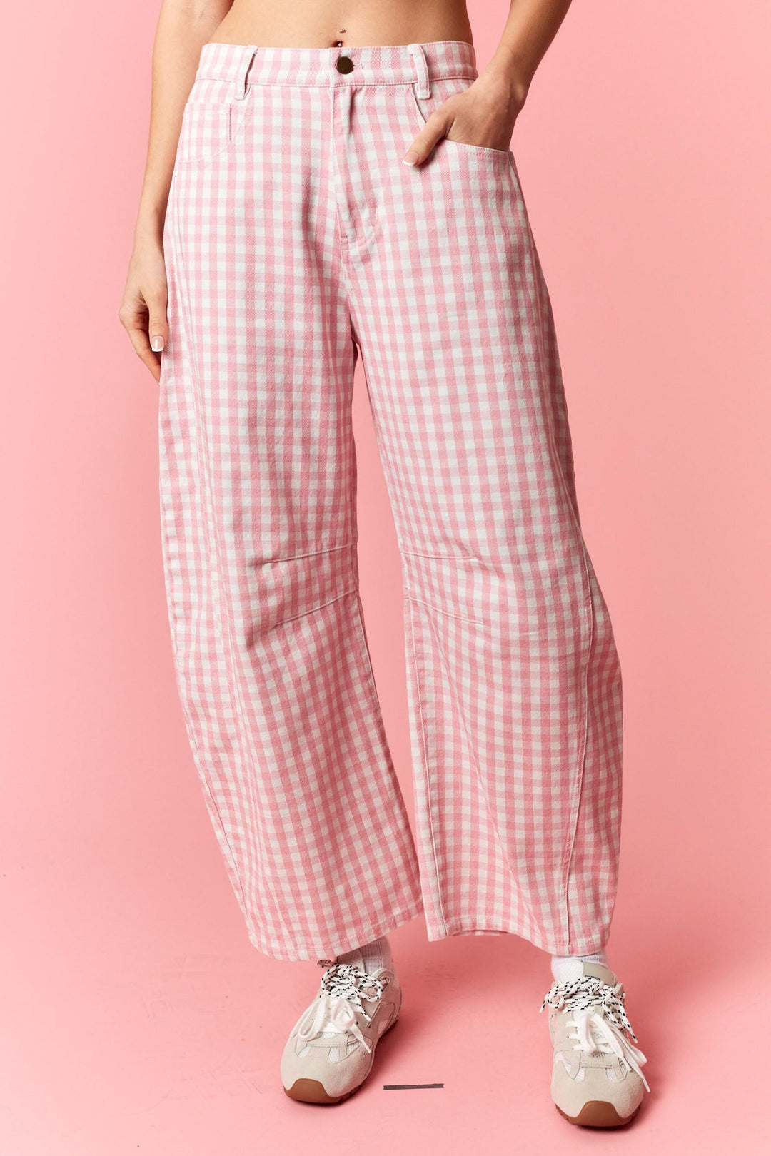 Person wearing pink and white checkered pants on a pink background