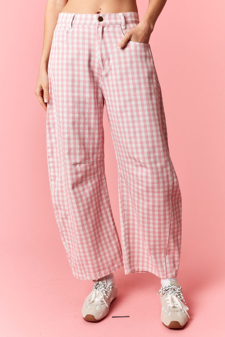 Person wearing pink and white checkered pants on a pink background